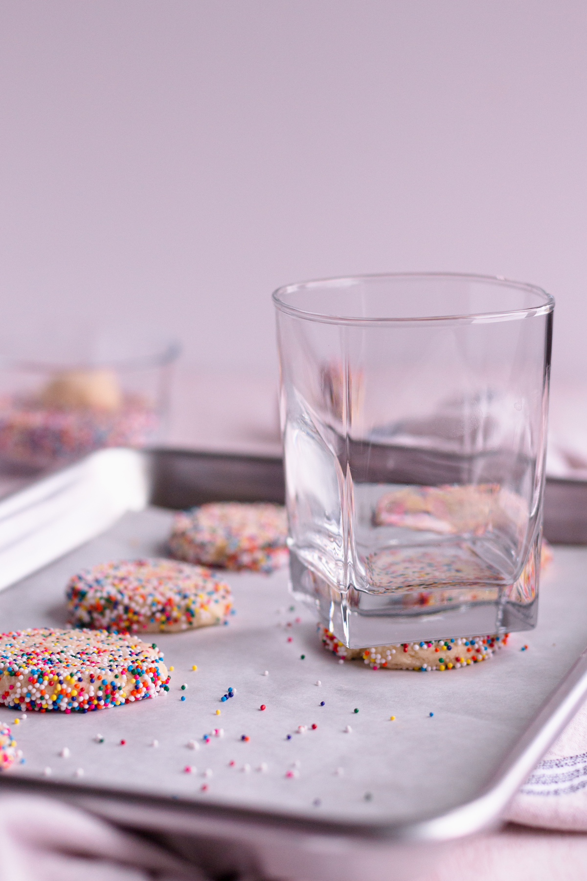 sugar cookies being pressed flat by a glass