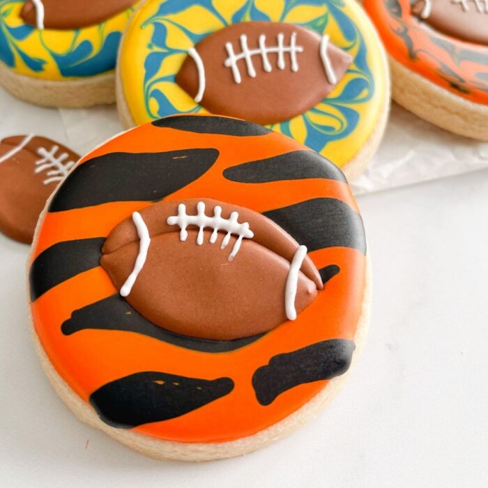 orange and black sugar cookie with a small football made of royal icing on it