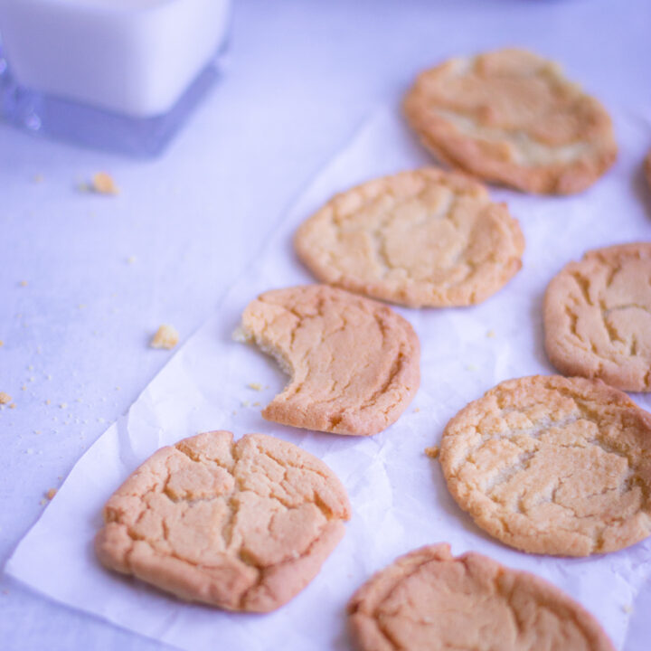 sugar cookies on a parchment paper with a bit taken out of one cookie