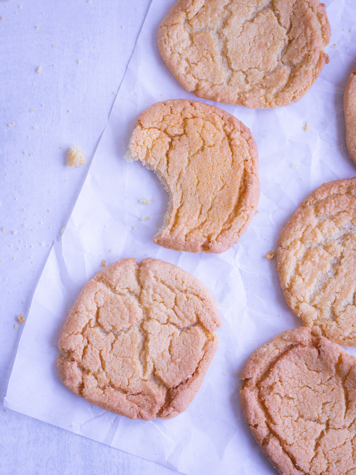 sugar cookies on parchment paper with one bite taken out of one of the cookies