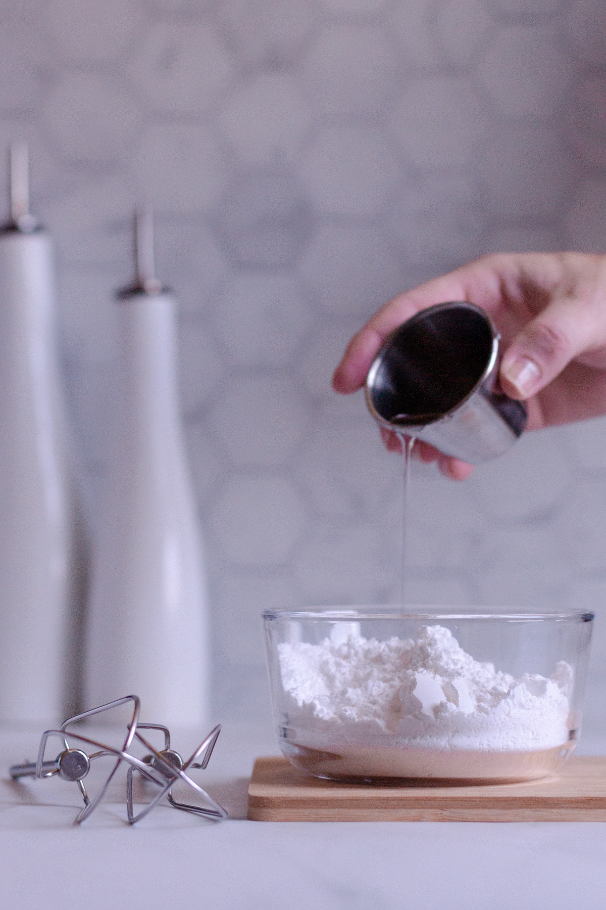 adding light corn syrup to a bowl of powdered sugar for royal icing