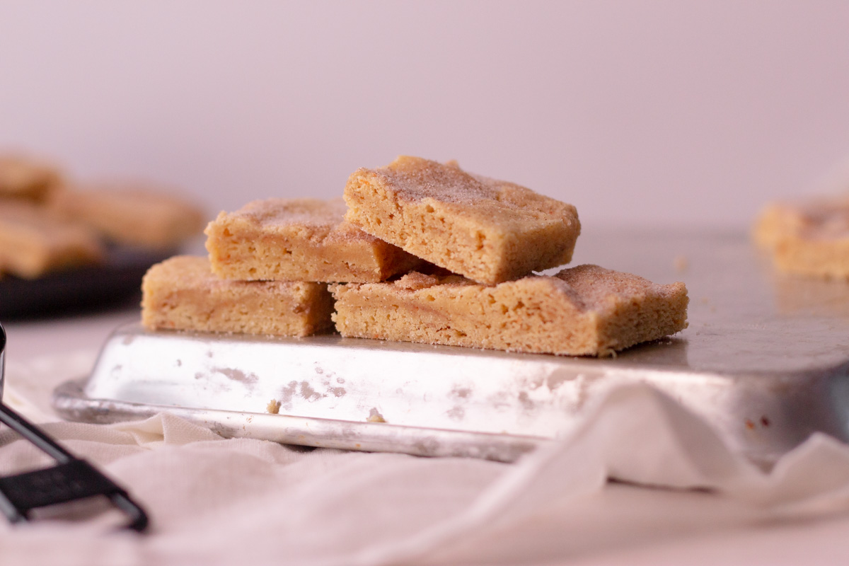 snickerdoodle cookie bars stacked up on a cookie sheet