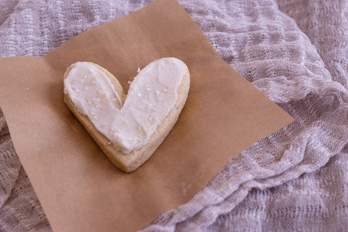 One heart almond sugar cookie on a small piece of brown parchment paper.