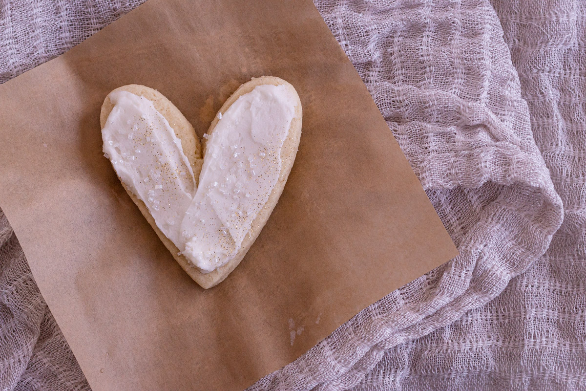 One heart almond sugar cookie on a small piece of brown parchment paper.