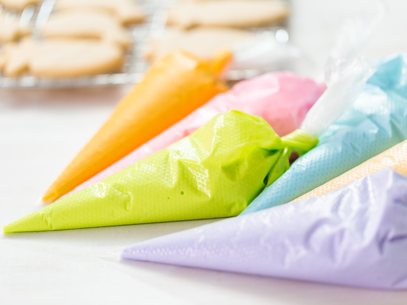 royal icing piping bags in orange, green, purples, blue, and pink