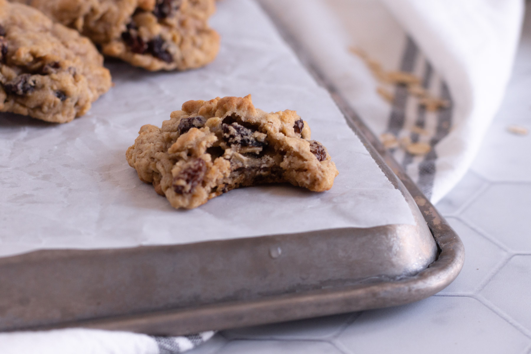 oatmeal raisin cookies on cookie sheet with a bit taken out of one of them