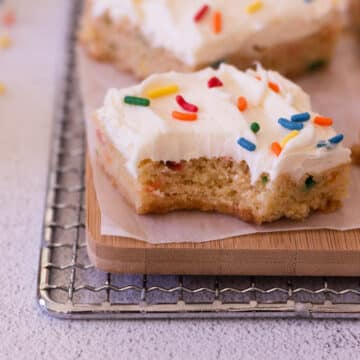 One square of the funfetti cookie bar on a wooden cutting board.
