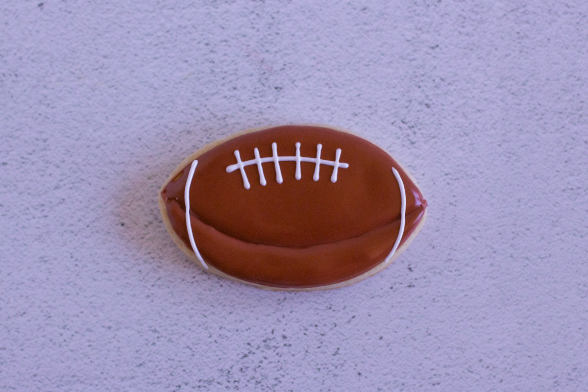 Football cookie completed with white royal icing accents. 