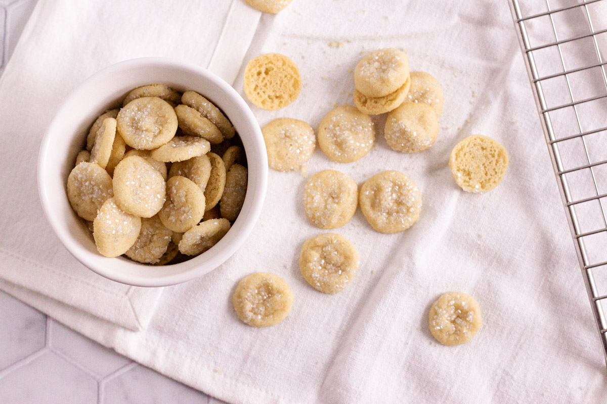 Mini sugar cookies in small bowl and spread across a napkin. 