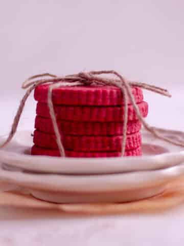 Stack of red velvet cut out cookies on a plate.