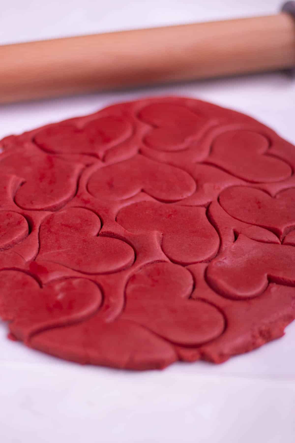 Heart cut-outs in the dough, next to a rolling pin. 