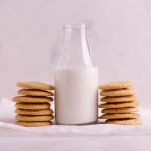 Small bottle of milk with two stacks of cookies.