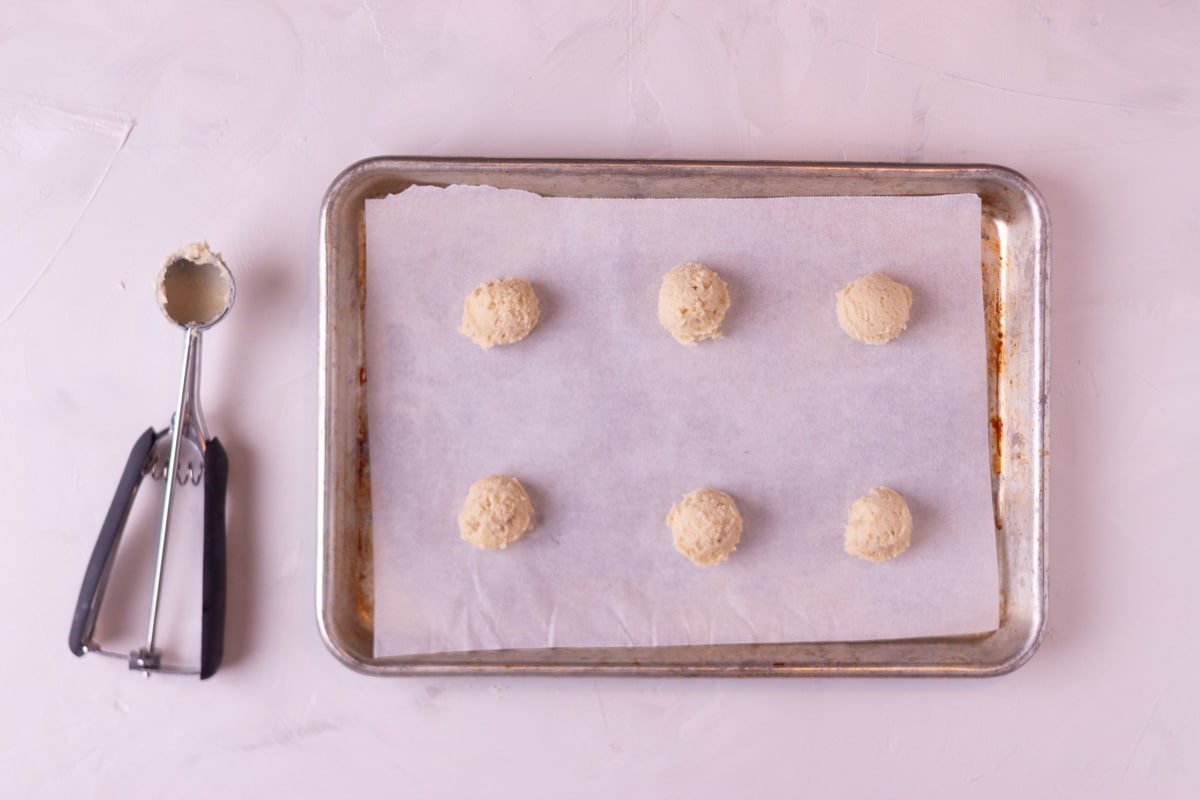 Cookie dough balls on a baking sheet before they go into the oven.